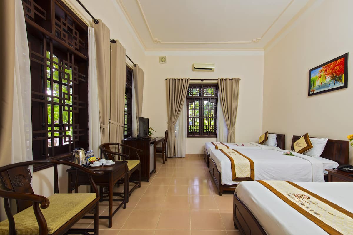 A hotel room with two beds, a desk with a chair, a television, and a window with curtains.