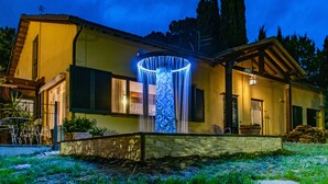 Une maison avec un bassin circulaire à l’avant, un chemin en pierre et un petit jardin.