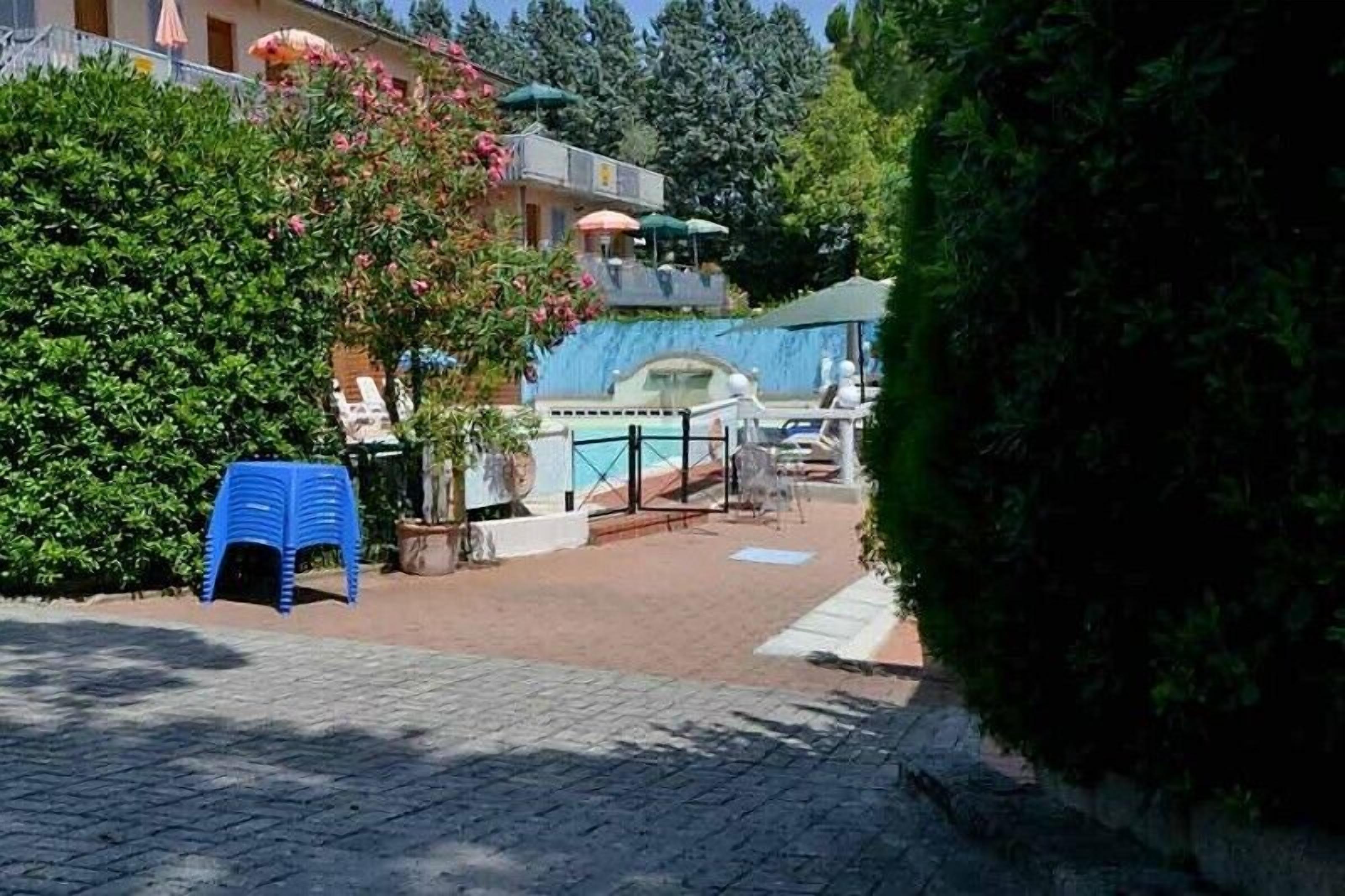 Ein Poolbereich mit blauem Liegestuhl, einer überdachten Sitzgelegenheit und einem Gebäude mit Balkon.
