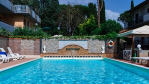 Une piscine bordée d’un muret en pierre, avec des chaises longues et un cercle de sauvetage.