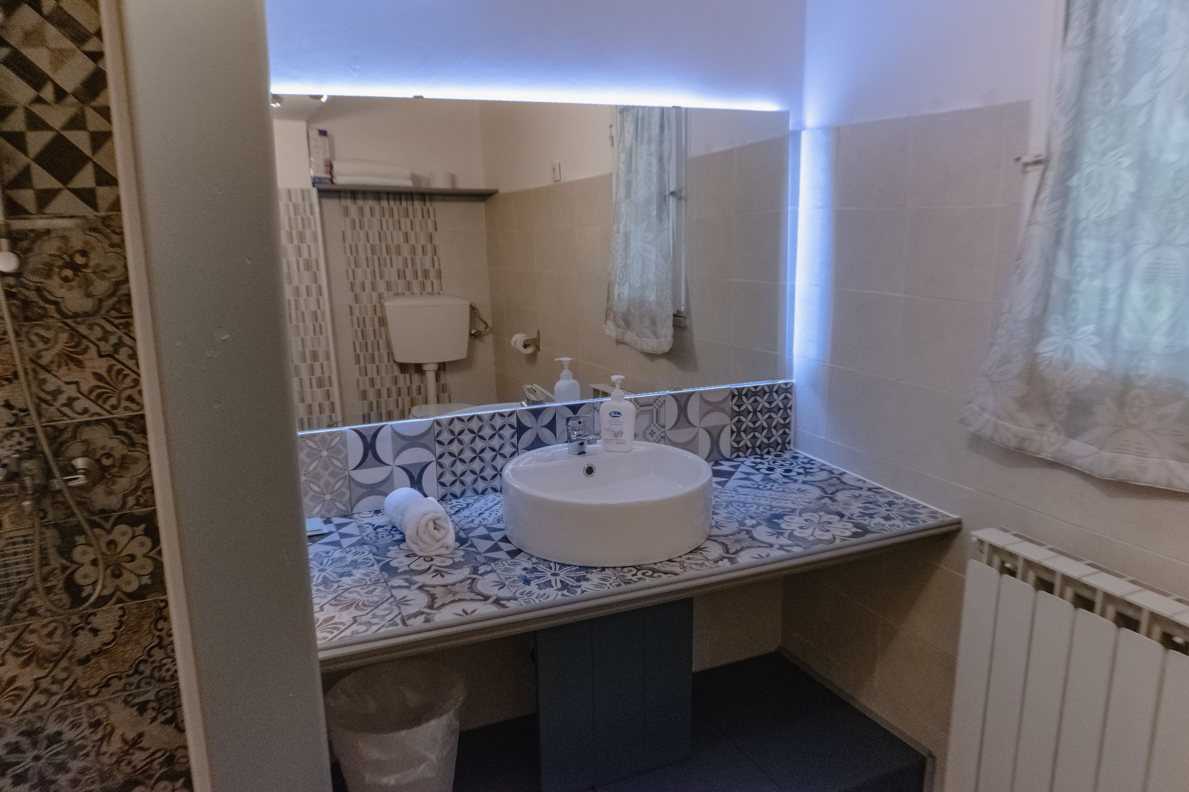 Une salle de bain avec des carreaux décorés, un lavabo avec un miroir et un porte-serviettes.