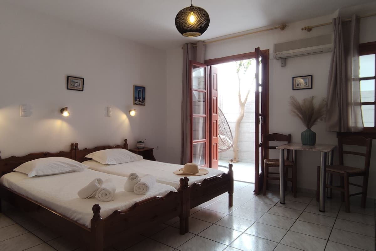 A bedroom with a bed, bedside tables, a desk, and a chair. There are wall-mounted lights and a window with curtains.