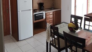 A kitchen with wooden cabinets, a white refrigerator, a stove, and a dining table with chairs.