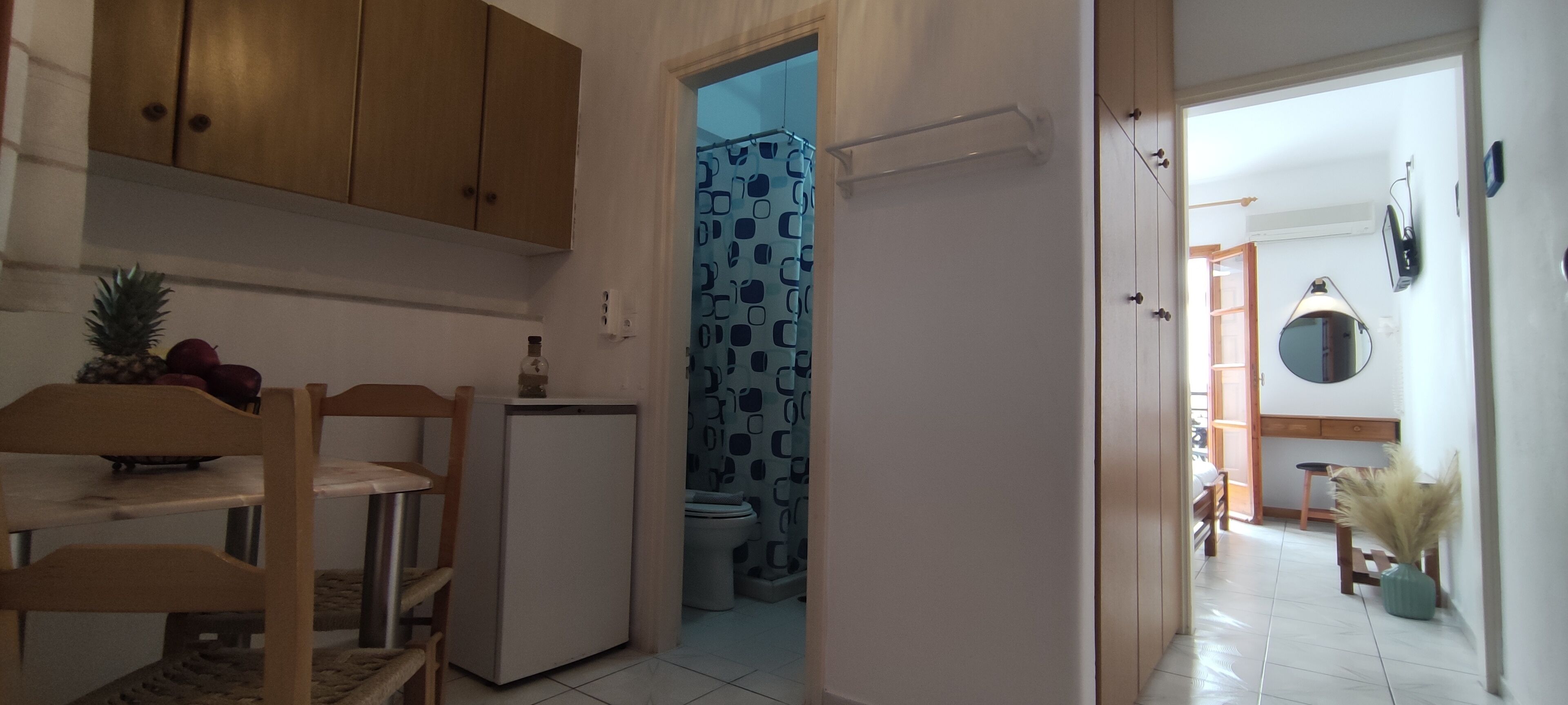 A kitchen with wooden cabinets, a refrigerator, and a dining area with chairs and a table.