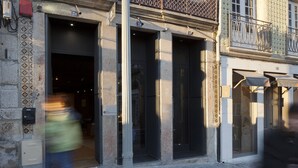 Ein Gebäude mit drei großen Eingängen, einem Metallgeländer im oberen Stockwerk und einem Muster aus Fliesen an der unteren Fassade.