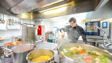 Een professionele keuken met roestvrijstalen apparatuur, potten en pannen op het aanrecht.