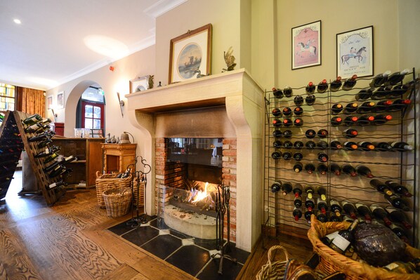 A cozy room with a fireplace, a wine rack, and a wooden floor.
