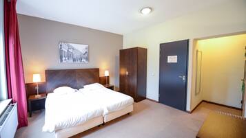 A hotel room with a bed, two bedside tables with lamps, a wardrobe, a door with a 'No Entry' sign, and a wall-mounted picture.
