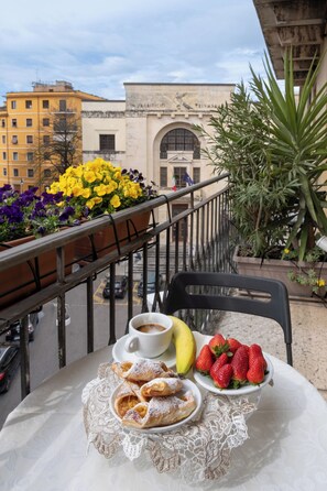 A balcony with a table set for breakfast, including pastries, strawberries, and a banana. - Bed & Breakfast Accademia (Verona)