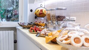 Un bufé con diferentes opciones de comida, incluyendo frutas, pasteles y una estación de café.
