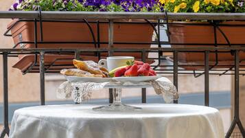 A table set with pastries, a cup, and a plate of strawberries, with flower pots in the background.