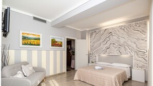 Un dormitorio moderno con cama, sofá y dos cuadros enmarcados en la pared.