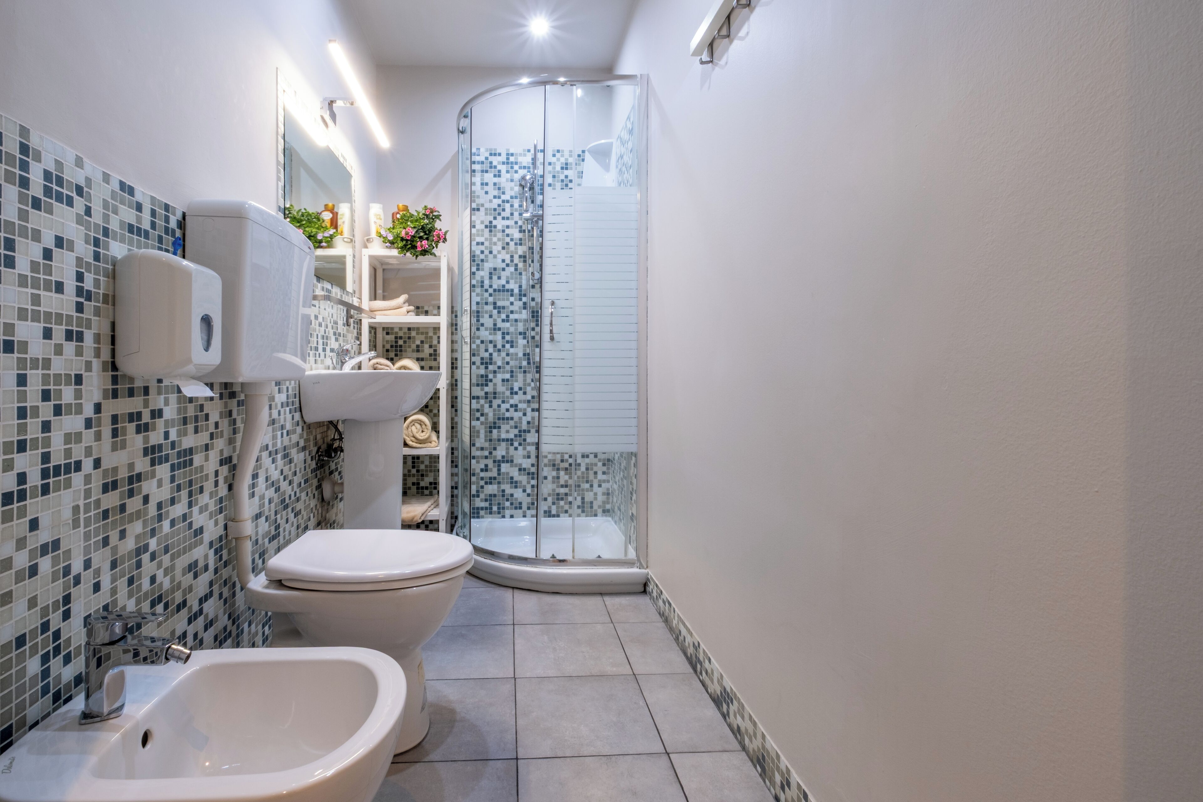 A modern bathroom with a bidet, toilet, and glass shower enclosure.
