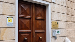 Puerta doble de madera con un letrero que indica zona de seguridad y una placa con un nombre.