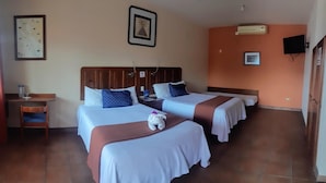 Une chambre d’hôtel avec deux lits, un bureau, une chaise, une télévision et une carte accrochée au mur.