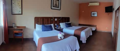 Quarto de hotel com duas camas, uma escrivaninha, uma cadeira, uma televisão e um mapa na parede.