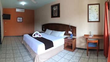 Una habitación de hotel con una cama, una mesita de noche, una silla y una pequeña mesa.