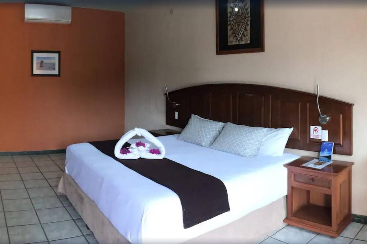 Una habitación de hotel con una cama, una mesita de noche, una silla y un mapa en la pared.