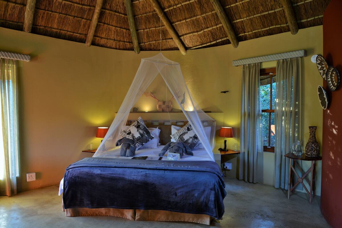 A bed with a canopy, a nightstand with a lamp, and a small table with decorative items.