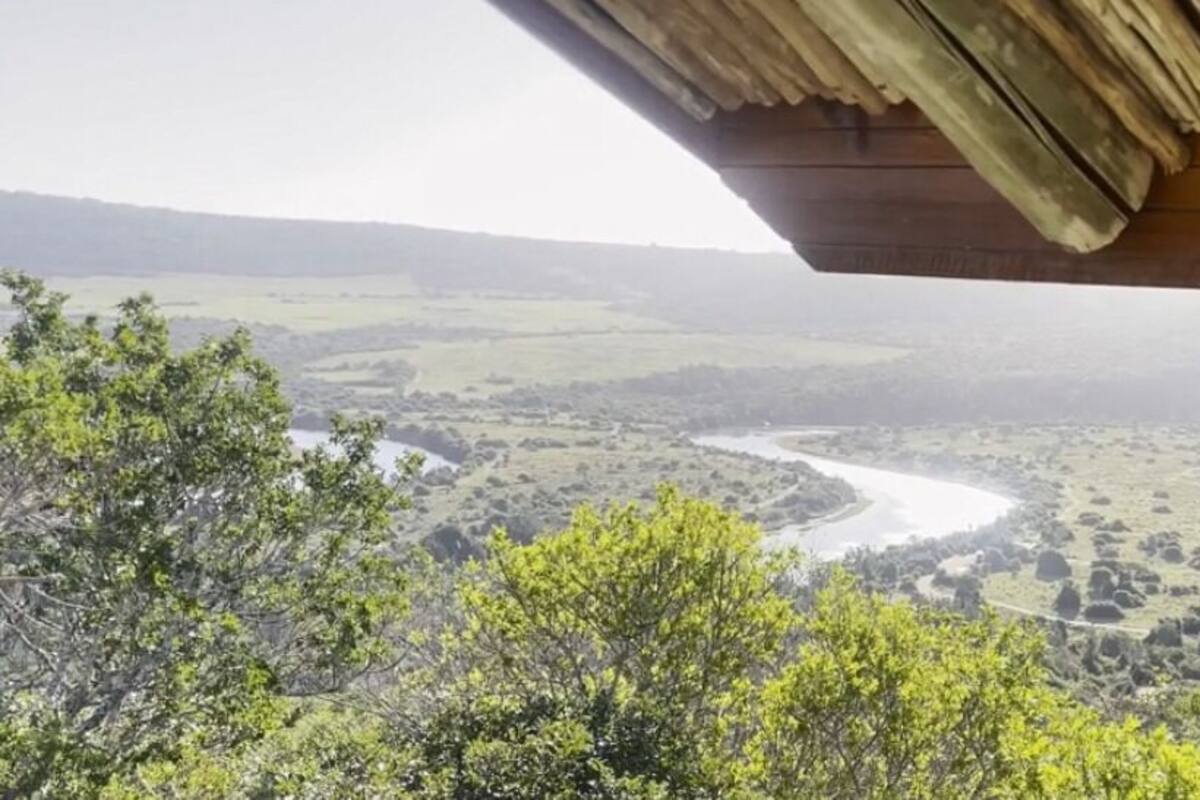 A view from a covered area overlooking a river and surrounding landscape.