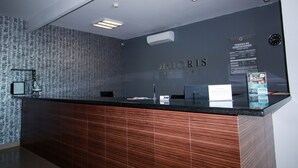 A hotel reception desk with a dark wood finish, a clock, and a sign indicating room rates. - Hotel  Maioris La Paz (La Paz)