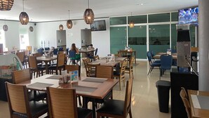 A modern restaurant with wooden tables and chairs, hanging wicker lamps, and a television screen. - Hotel  Maioris La Paz (La Paz)