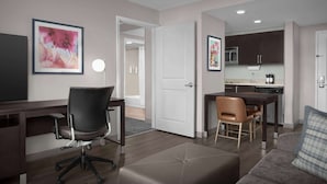 A modern apartment with a living room, a dining area, and a kitchen. There is a desk with a chair, a sofa, and a coffee table. - Homewood Suites by Hilton Orlando Airport (Orlando)