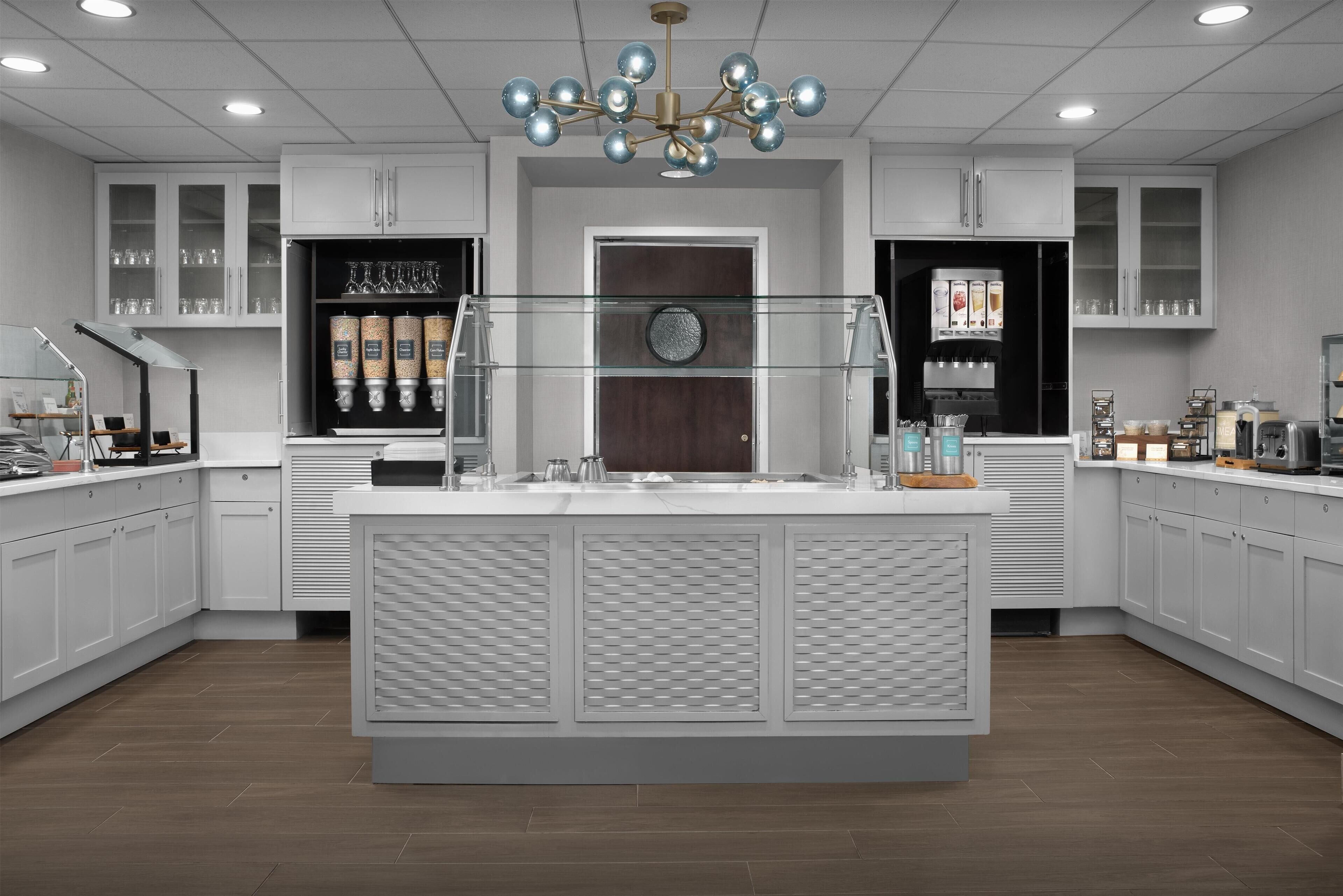Una cocina moderna con armarios blancos, una isla central y una araña.