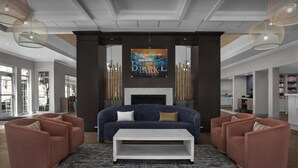 A modern living room with a sofa set, a coffee table, and a fireplace. - Homewood Suites by Hilton Orlando Airport (Orlando)