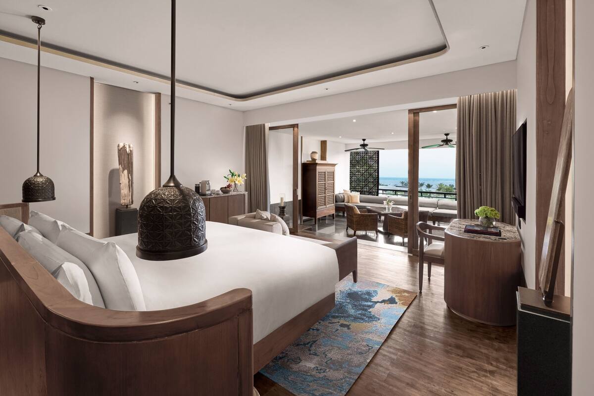 Une chambre d’hôtel moderne dotée d’un grand lit, d’un coin salon et d’une vue sur l’océan.
