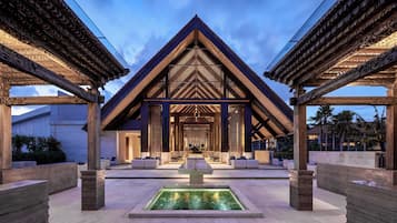 A modern building with a triangular roof, a central courtyard with seating, and a water feature.
