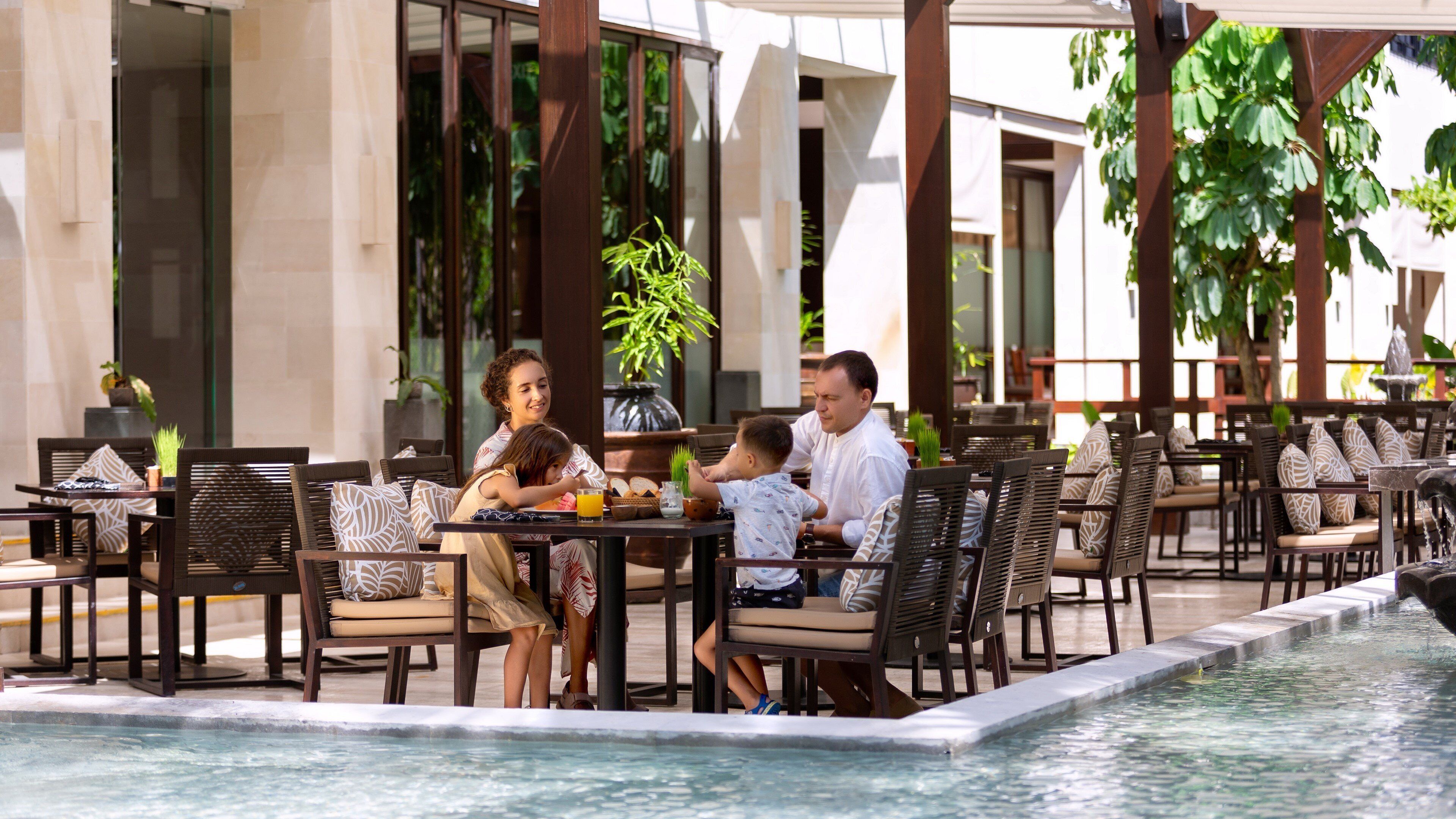 A poolside dining area with outdoor seating and a water feature.