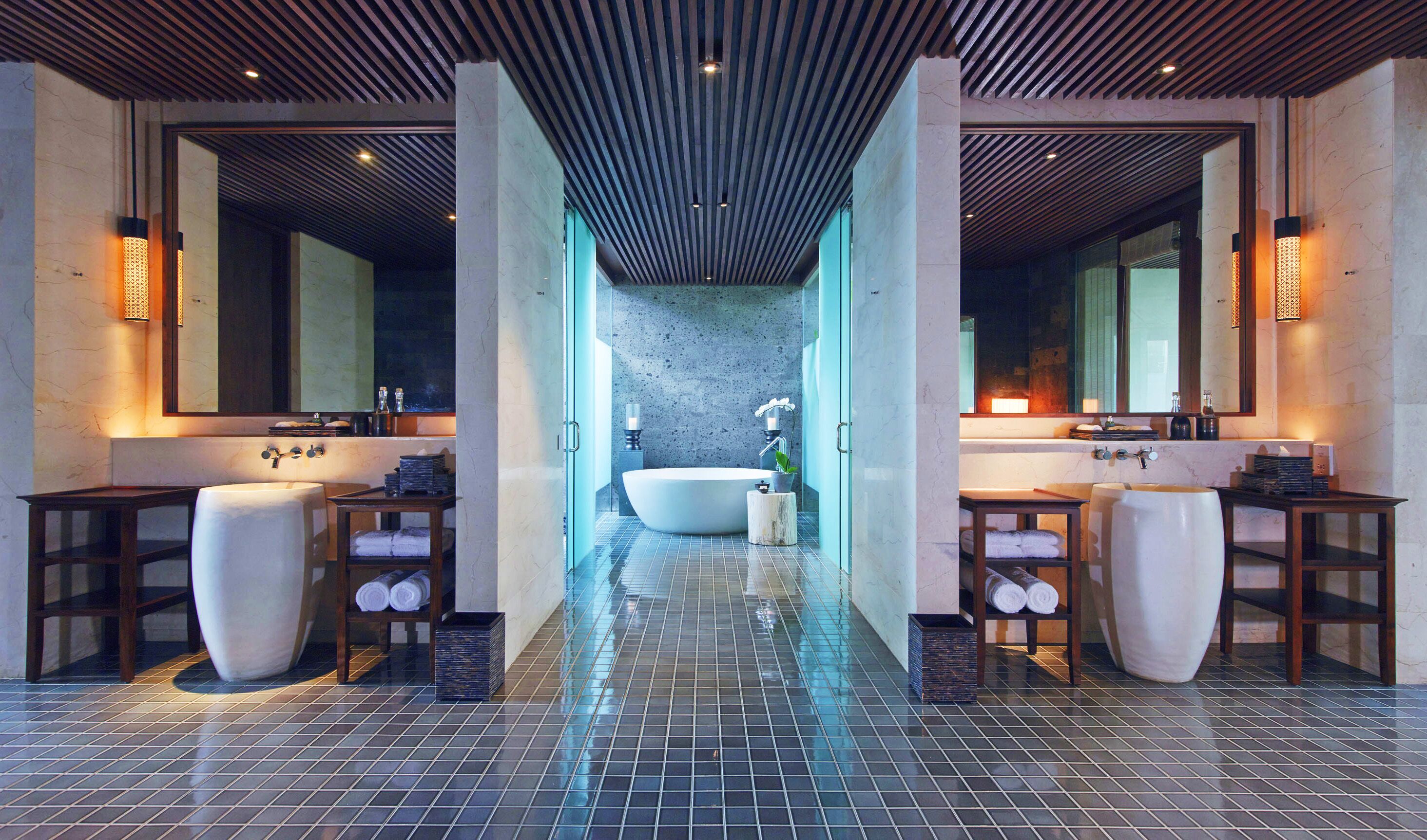 A modern bathroom with a large bathtub, two sinks, and a mirror.