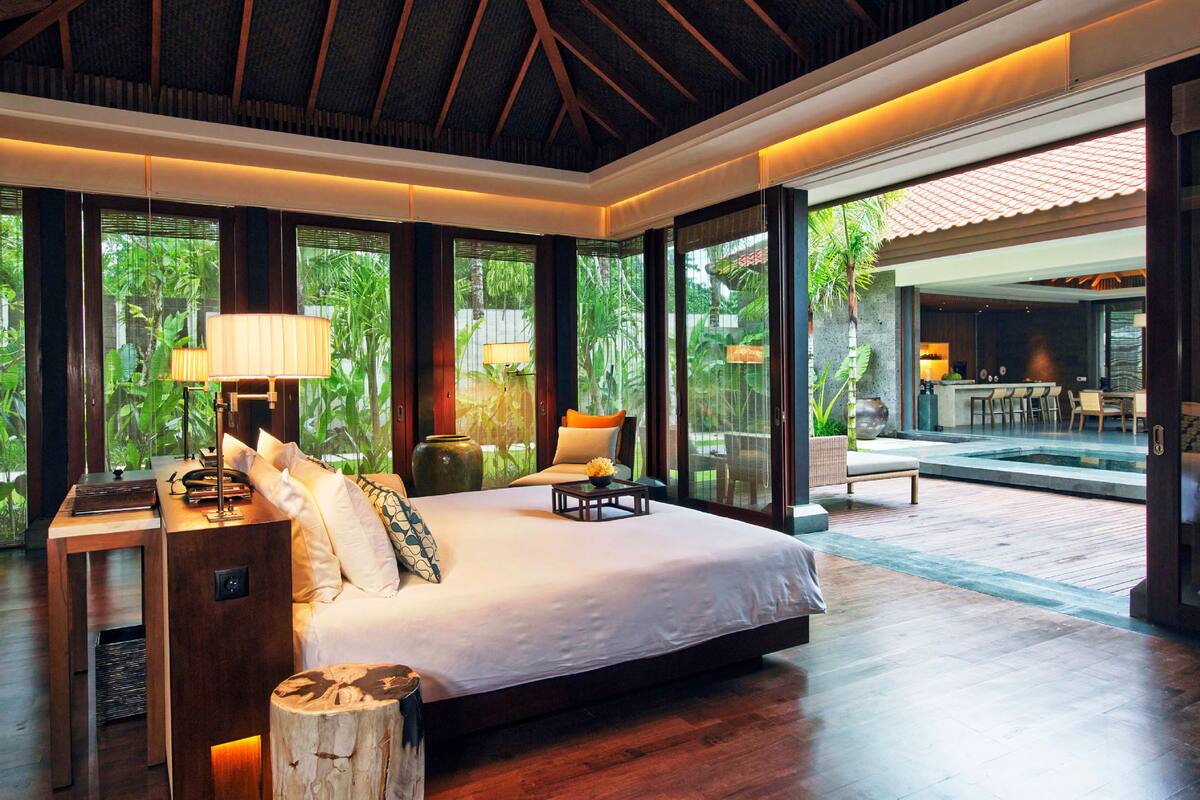 Une chambre spacieuse avec un grand lit, un plancher en bois et une vue sur une piscine et un espace extérieur.