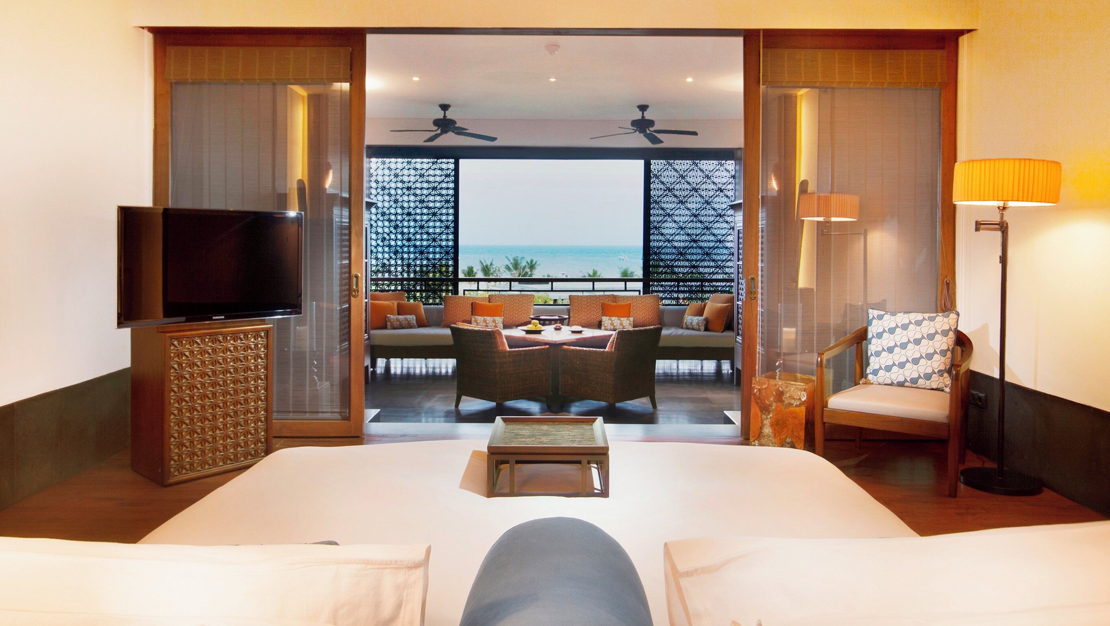 Une chambre d’hôtel comprenant un lit, une télévision, un coin repas avec une table et des chaises, et donnant sur l’océan.