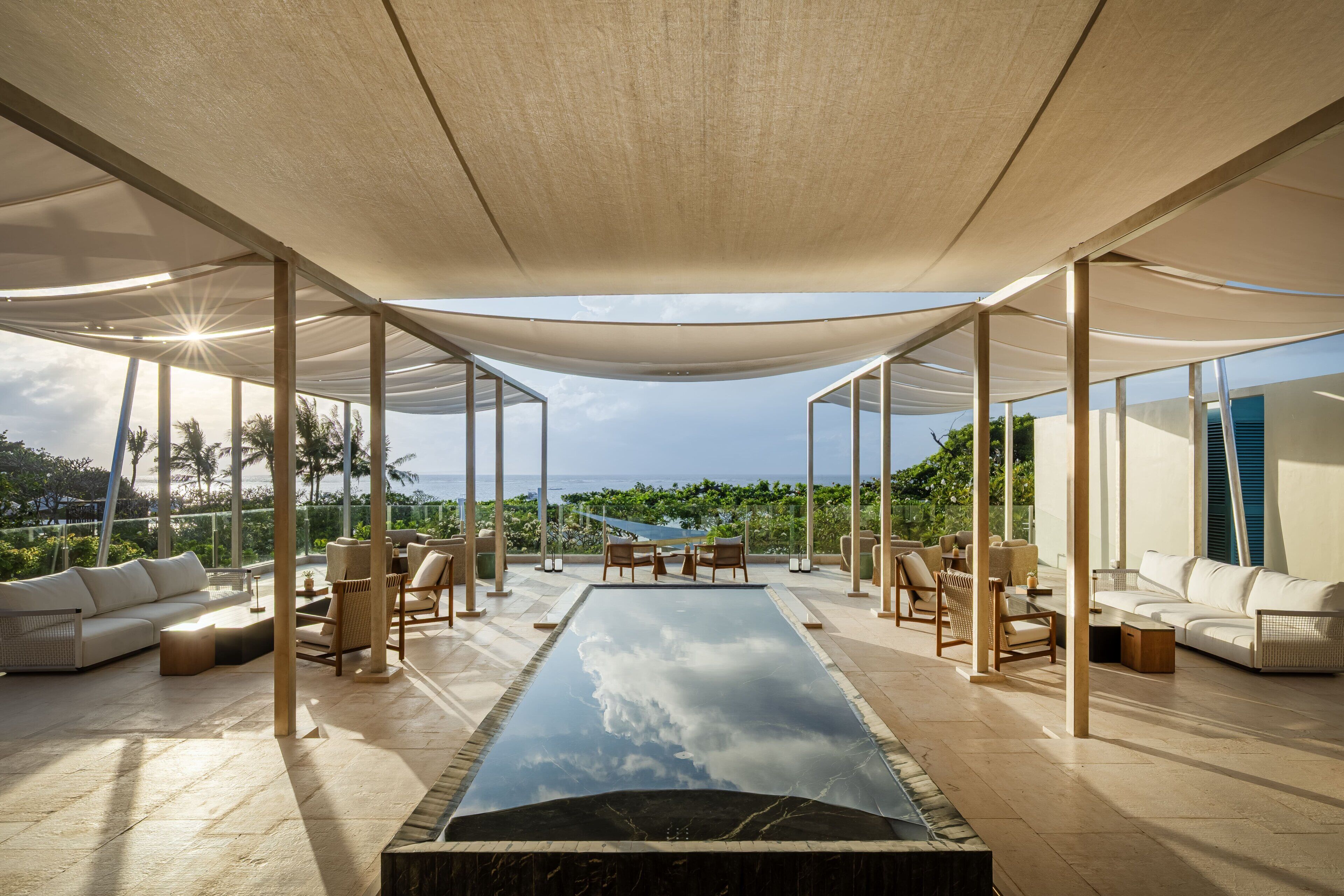 Un espace de détente extérieur moderne, doté d’une piscine, de sièges et offrant une vue sur l’océan.