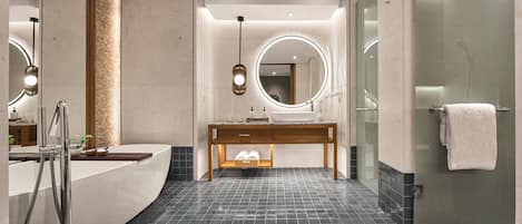 A modern bathroom with a curved vanity, a round mirror, a glass shower enclosure, and a tiled floor.