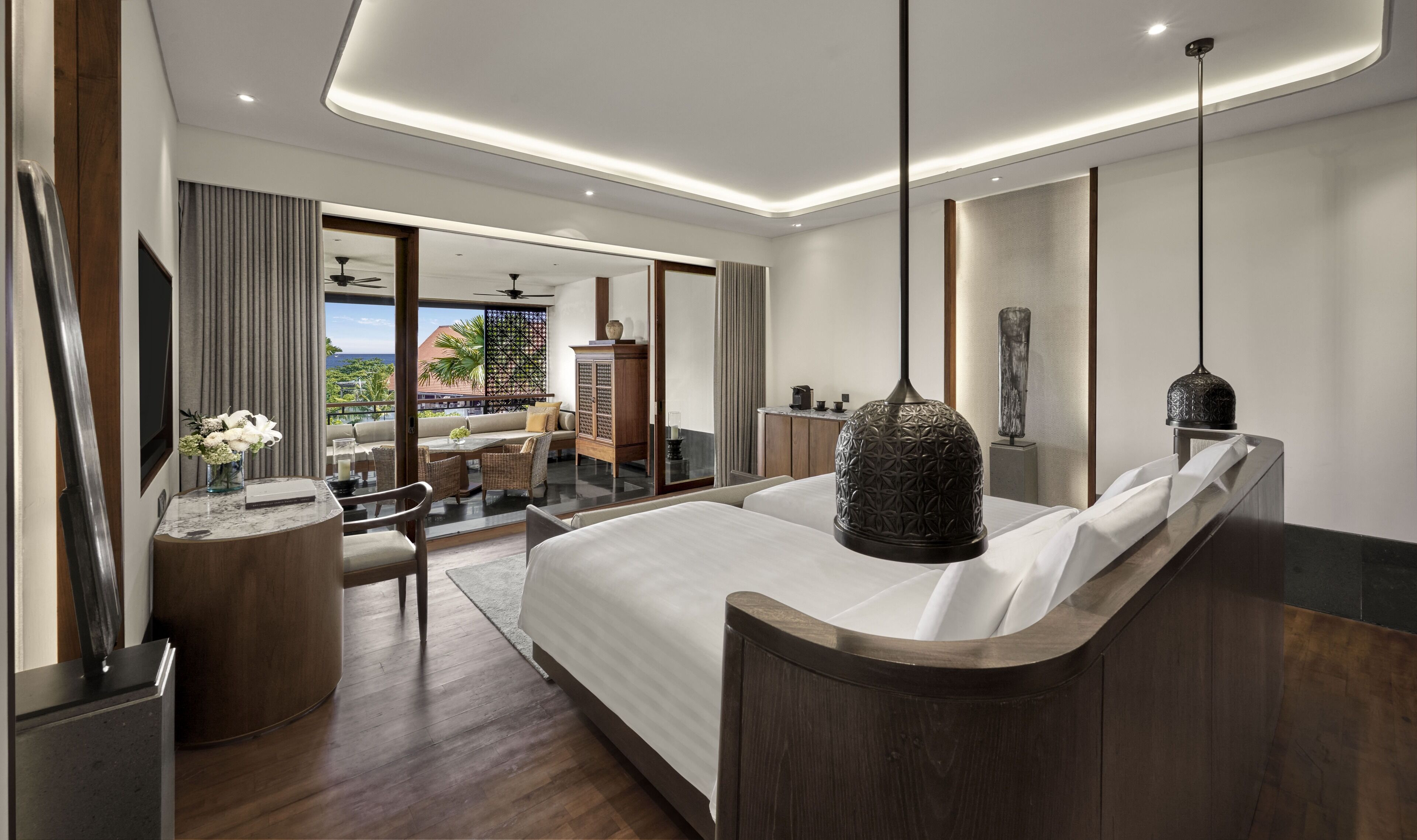 Une chambre d’hôtel moderne dotée d’un grand lit, d’un coin repas et offrant une vue sur l’océan.