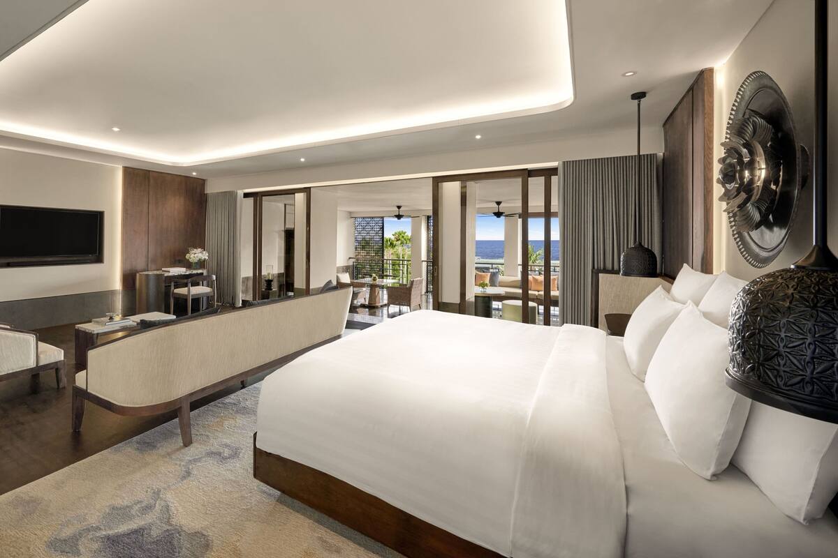 Une chambre d’hôtel moderne avec un grand lit, un bureau et un balcon offrant une vue agréable.