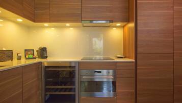 Una cocina moderna con armarios de madera, horno empotrado y enfriador de vinos.