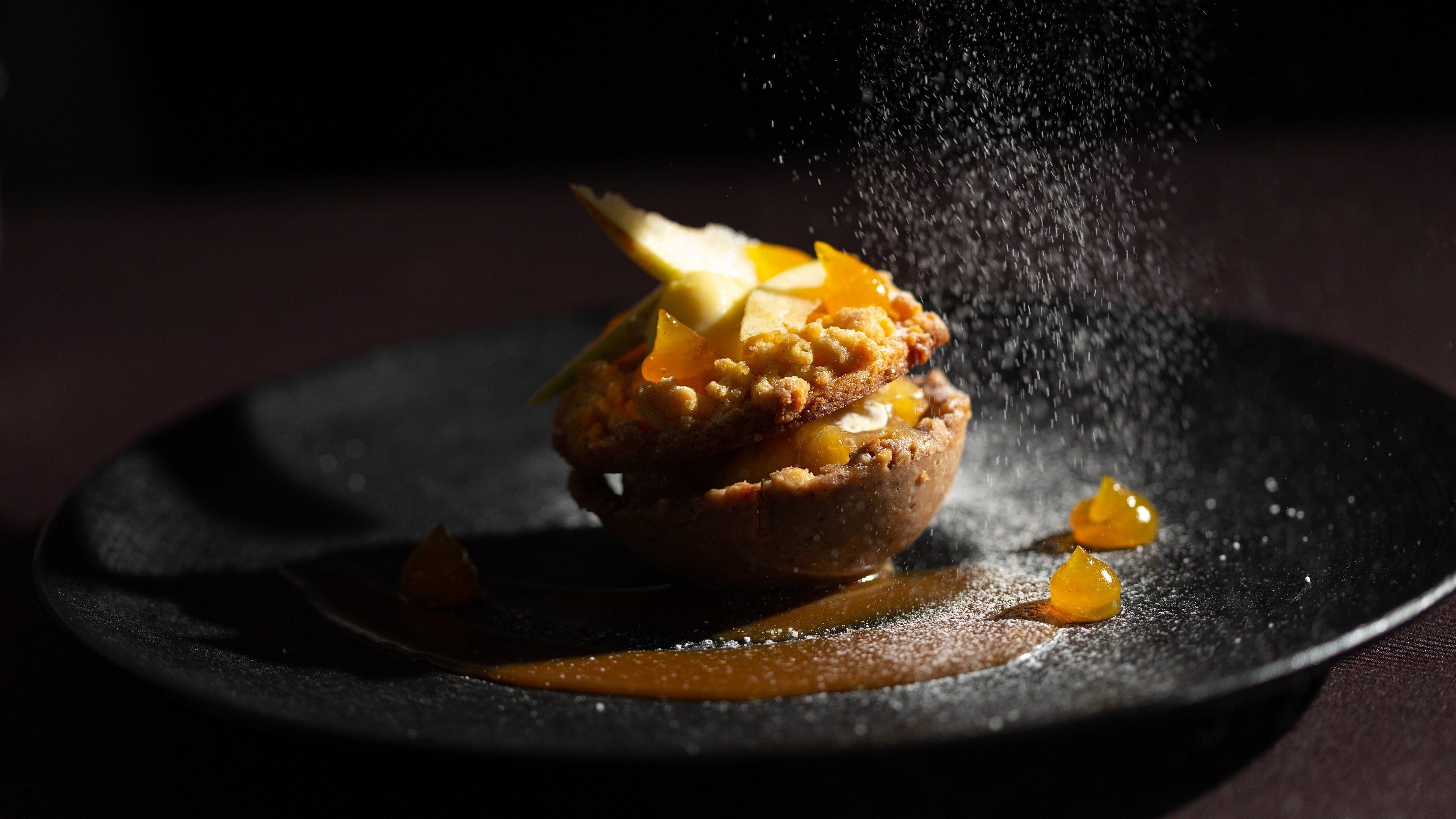 Un postre sobre un plato oscuro con superficie texturizada, posiblemente de chocolate o material similar a la piedra.