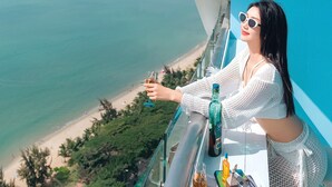 A balcony with a clear view of the beach and ocean, a bottle of liquor, and a glass on the table. - Four Points by Sheraton Hainan, Sanya (Sanya)