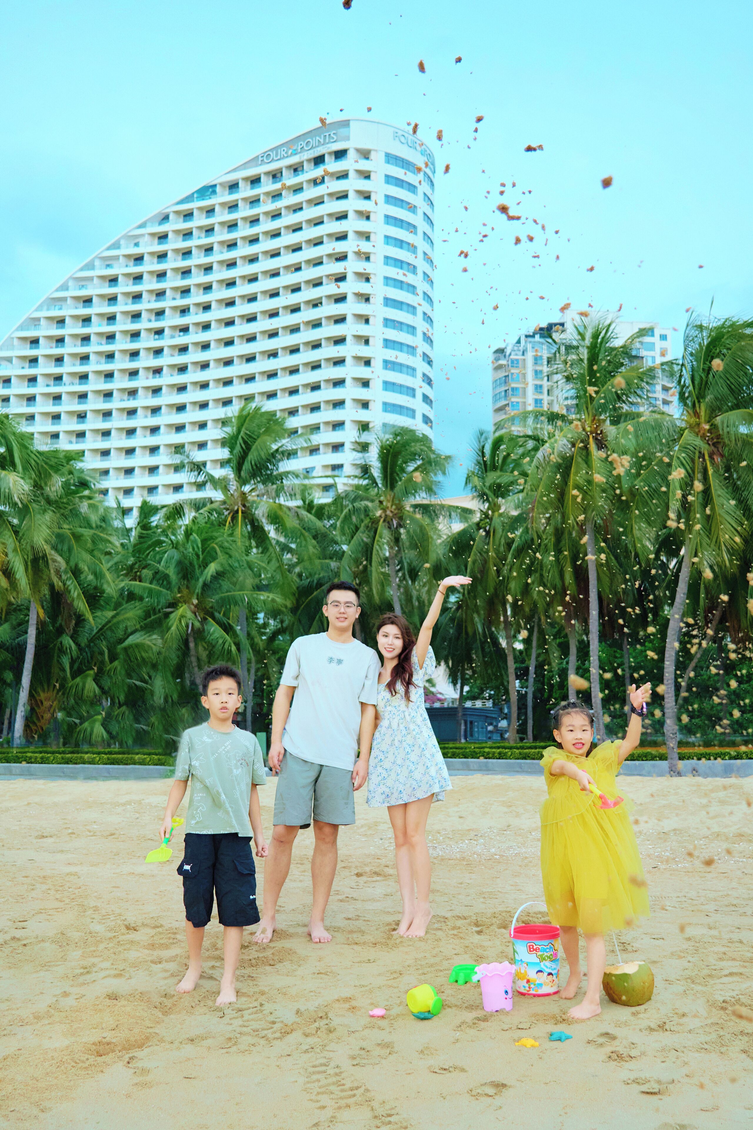 A family on a sandy beach with palm trees and a tall hotel in the background.