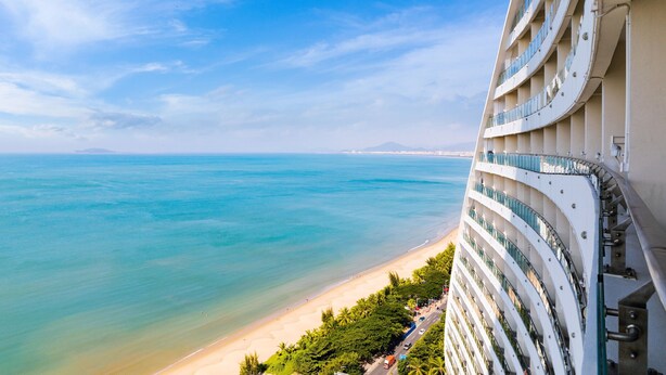 A high-rise hotel with balconies overlooking a beach and ocean. - Four Points by Sheraton Hainan, Sanya (Sanya)