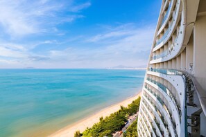 A high-rise hotel with balconies overlooking a beach and ocean.