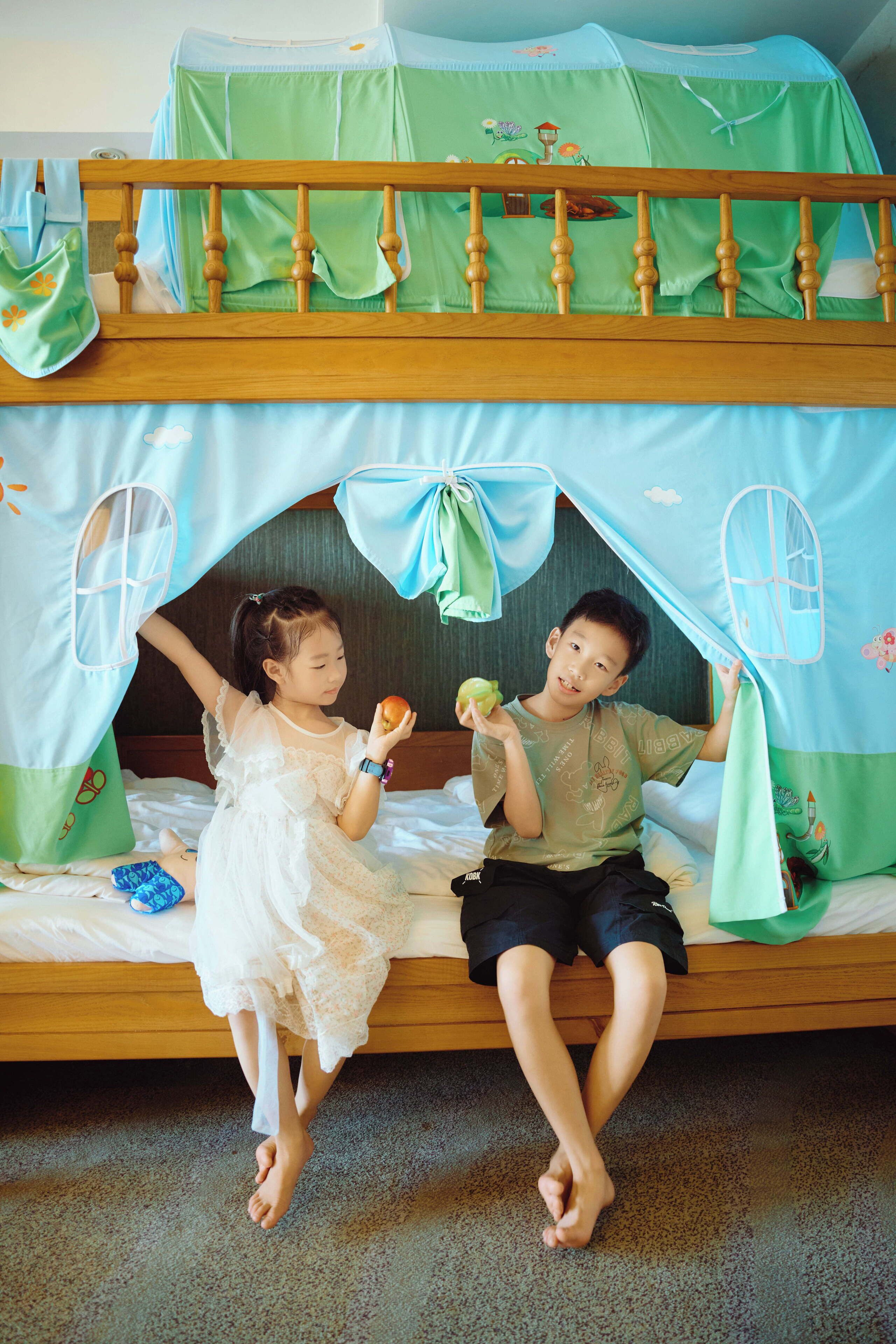 A bunk bed with a canopy, a child in a white dress, and another child in a green shirt.
