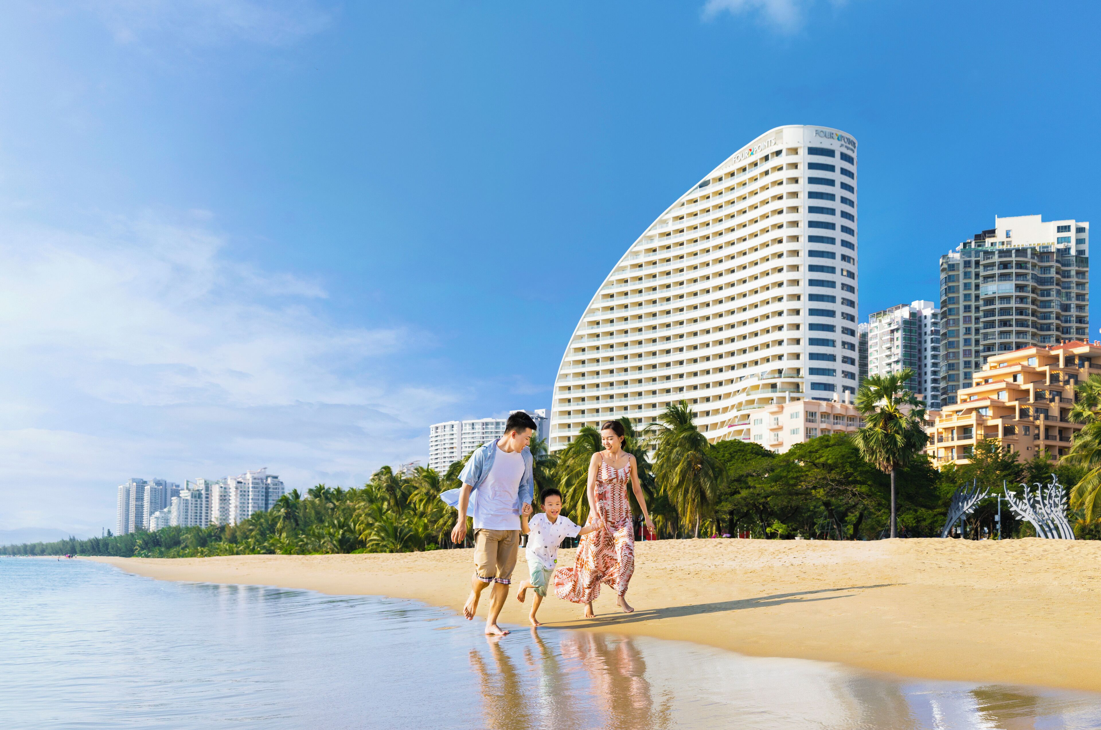 Un hotel frente al mar con un edificio curvo, palmeras y cielo despejado.
