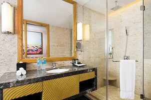 Un baño moderno con lavamanos de mármol, un espejo grande y una ducha con mampara de vidrio.