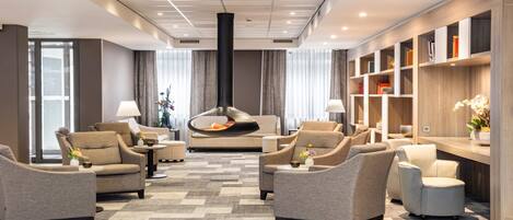 A modern living room with sofas, a fireplace, and a bookshelf.