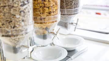 En matserveringsstation med flera behållare som innehåller müsli och andra snacks.